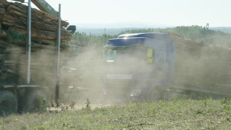 Trucks-full-of-lumber-kick-up-dust-as-they-drive-past