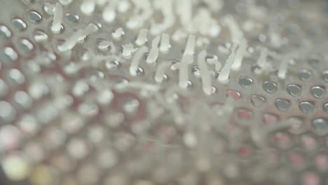 Macro-shot-of-cheese-being-grated-inside-of-grater