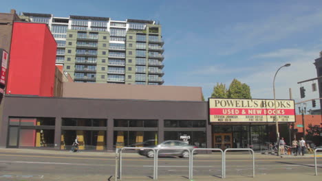 Powell's-Books-sign-on-West-Burnside-downtown-Portland,-Oregon,-USA-with-people-and-cars-passing-by