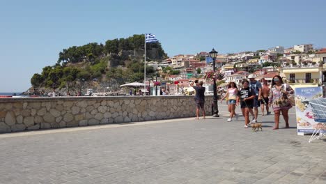 People-walking-on-stone-walkway-at-noon-at-Parga-Greece,-static-shot