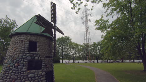 Schöne-Aussicht-Auf-Windmühle,-Mühle-In-Natürlichem-Grünen-Park,-Gras,-Bäume-Und-Bewölktem-Himmel