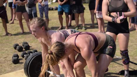 A-Pair-of-Female-Athletes-Doing-Team-Dead-Lifts-in-Front-of-a-Crowd-of-Spectators-at-a-Cross-Fit-Competition