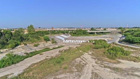 Drone-Aéreo-Sobre-Cintura-Arbustos-Terrestres-Arbustos-Y-árboles-Con-Cielos-Azules-Y-Autopista-En-El-Fondo