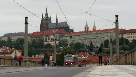 Elektrische-Straßenbahn-überquert-Brücke-In-Prag-Mit-Burg,-Kathedrale-Und-Gotischer-Architektur-Im-Hintergrund