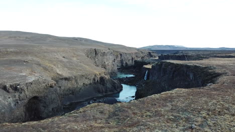 Drone-Aerial-View-of-Volcanic-River-Canyon-and-Blue-Glacier-Melted-River-Water,-Icelandic-Highlands