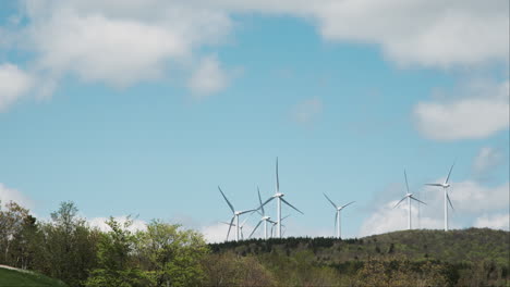 Windräder-Drehen-Sich-Majestätisch-Vor-Einem-Blauen-Himmel,-Der-Von-Dünnen-Wolken-Durchzogen-Ist