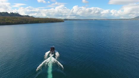 Aerial-orbit-shot-of-a-fishing-boat-navigating-on-a-lake-in-New-Zealand