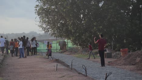 Male-with-a-mobile-phone-taking-a-panorama-picture-in-Galle-Fort,-Crowd-walks-freely-in-fort-pathways-in-the-evening-time