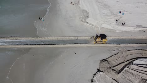 Ein-Raupen-Bulldozer-Mit-Schweren-Maschinen-öffnet-Einen-Durchgang,-Durch-Den-Wasser-Aus-Dem-Naturschutzgebiet-Zandvlei-Mündung-In-Den-Muizenberg-Strand-Fließen-Kann