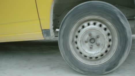 Close-up-of-wheel-of-yellow-surf-van-driving-through-countryside