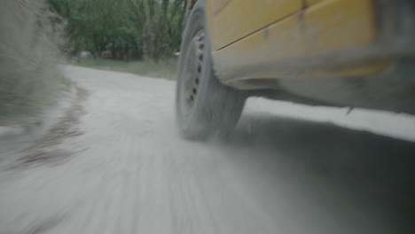 Close-up-of-wheel-of-yellow-surf-van-driving-through-countryside