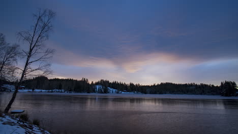 Time-lapse-shot-of-dark-clouds-above-a-lake-and-forest,-winter-sunset,-in-Risvann,-Agder,-South-Norway