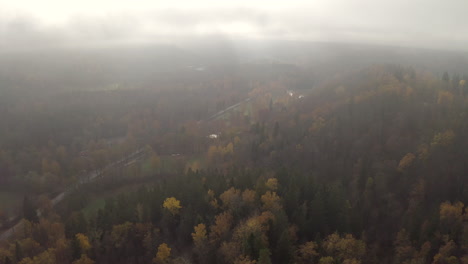 Drone-Descendiendo-De-Las-Nubes-En-Un-Valle-Con-Una-Sola-Carretera-Y-Senderos-Para-Caminar-Y-Varios-Estanques-Y-Un-Río-Al-Fondo