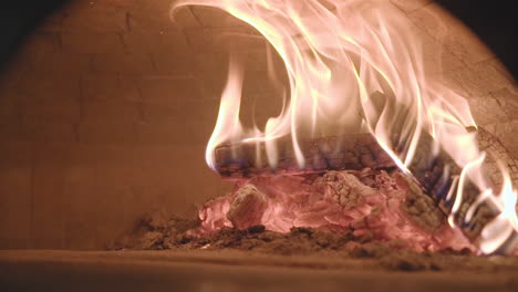 Fire-blazing-inside-Naples-style-wood-burning-pizza-oven,-medium-dolly-in-slow-motion