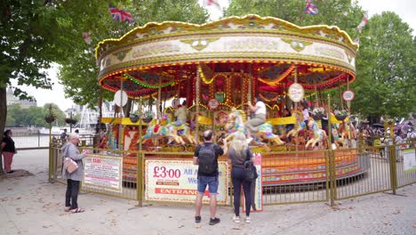 Merry-go-round,-or-carousel,-spinning-during-daytime-by-the-river-Thames-in-London