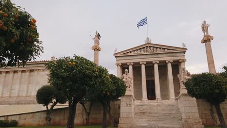 Tiro-En-Movimiento-Lento,-Naranjo-Y-Estatua-De-Platón,-Academia-De-Atenas,-Grecia-Al-Fondo