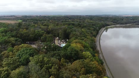 Real-estate-Stone-mansion-tucked-away-in-green-forest-and-river,-Aerial-long-shot