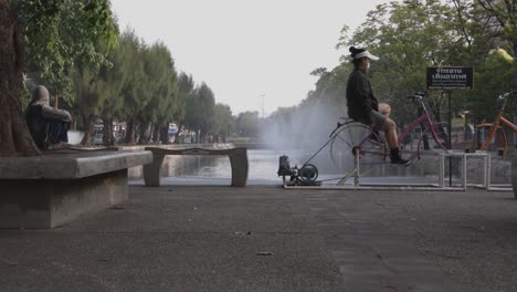 A-woman-wearing-face-mask-is-exercising-on-an-exercise-bike-at-a-public-outdoor-gym-next-to-Chiang-Mai-city-moat-during-COVID-19