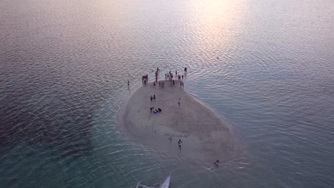 Aerial-view-of-Tourist-on-a-small-island-or-islet-enjoying-sunset-in-Philippines,-Palawan