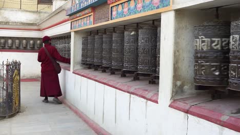 Buddhist-monk-rolling-the-prayer-wheels-in-Kathmandu,-Nepal