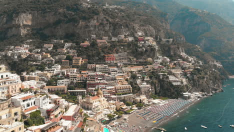 Antena-De-Positano,-Inclinada-Hacia-Arriba,-Vista-De-Drones,-En-Un-Día-Soleado-De-Verano,-Revelando-Hermosas-Montañas-Y-La-Playa-Con-Colores-Increíbles-En-La-Costa-De-Amalfi,-Italia