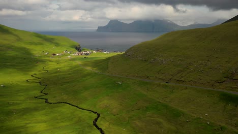 Vista-Aérea-Siguiendo-El-Coche-A-Lo-Largo-De-La-Carretera-Montañosa-De-Las-Islas-Feroe-Hacia-Gjógv