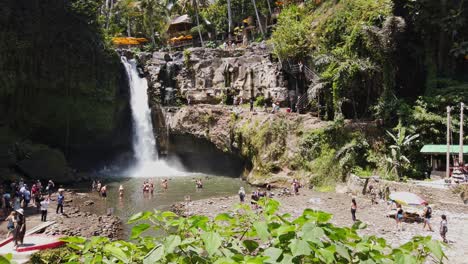 Tourist-enjoying-the-scenic-Tegenungan-waterfall-in-a-lush-forest-setting-with-shallow-pool-popular-for-swimming