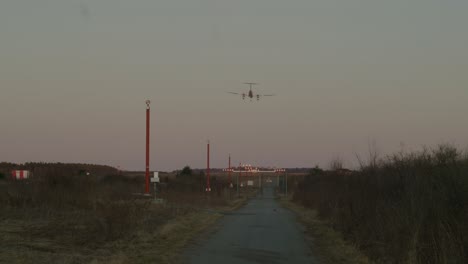 A-large-King-Air-propellor-plane-lands-at-sunset,-viewed-from-the-end-of-the-runway