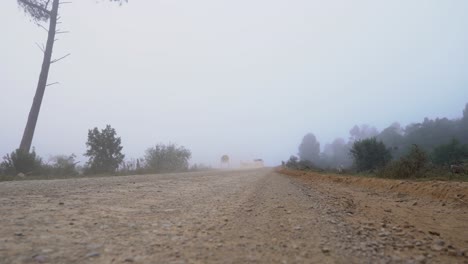 Truck-Drives-Into-Mist-On-An-Old-Country-Dirt-Road-Early-In-The-Morning