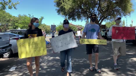 Young-people-carrying-signs-in-protest-of-police-brutality-in-wake-of-death-of-George-Floyd,-killed-by-Minneapolis-police-officer-last-week