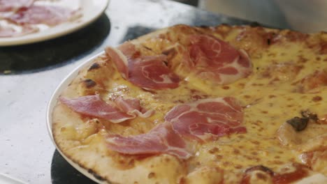 Pizza-maker-cooks-pizza-with-bacon