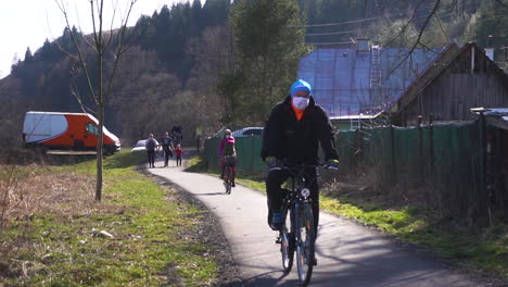 Personas-Que-Usan-Máscaras-Mientras-Andan-En-Bicicleta-En-La-Calle-Cerca-De-Bratislava,-Eslovaquia-Durante-El-Brote-De-Covid-19---Cámara-Lenta