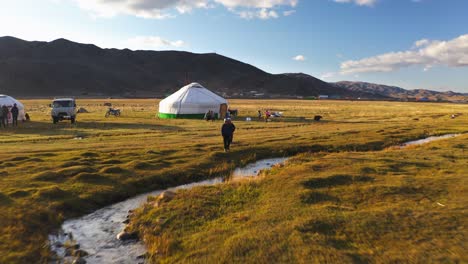 Aerial:-Young-nomadic-Mongolian-children-playing-outside-ger-tents-in-Altai-Mountains,-done