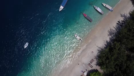 Aufsteigende-Luftaufnahme-Des-Strandes-Von-Gili-Trawangan-Auf-Bali-Mit-Booten,-Die-In-Der-Nähe-Des-Sandes-Festgemacht-Sind