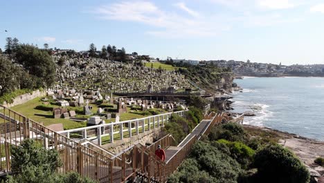 Waverley-Cemetery-located-on-the-Cliffs-at-Bronte-near-Clovelly-Beach-with-people-walking-up-steps,-Locked-shot