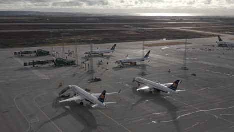 Stunning-sunlight-shines-over-quiet-airport-with-grounded-airplanes,-aerial