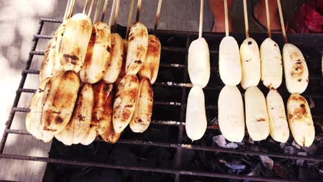 Close-up-shots-of-cardava-banana-on-bbq-fire-stand-with-skewers