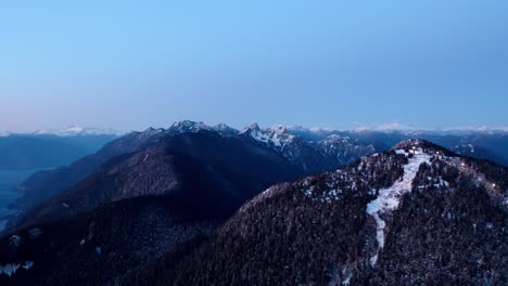 Aerial-view-of-lightly-snowed-on-Mountain-at-Dusk