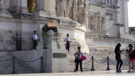 Tourists-Taking-Selfie-in-Front-of-Fire-Goblet-Burning-in-Rome-With-Guards-on-Both-Sides