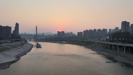 Beautiful-sunset-view-of-JiaLing-river-with-constructing-bridge-in-background,-ChongQing,-China