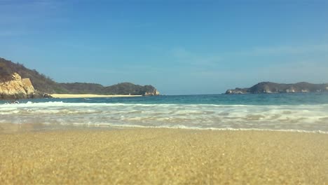 Calm-waves-hitting-the-lens-on-the-shore-of-an-empty-beach,-Huatulco-bay,-Mexico