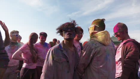 Young-man,-long-hair-and-sunglasses,-Jumping-up-and-down,-Dancing-at-Holi-Festival