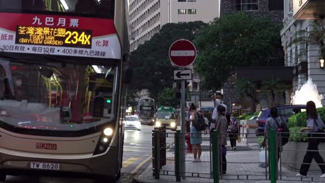 A-double-decker-passenger-bus-driving-along-the-traffic-and-passes-by-the-pedestrian-lane-and-turns-to-the-right