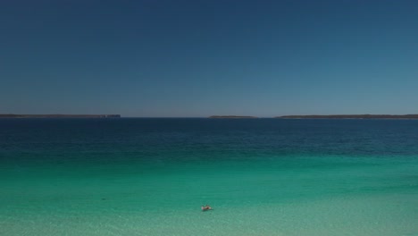 Aerial-view-of-people-on-a-white-sand-beach,-in-sunny-Jervis-bay,-NSW,-Australia---ascending,-drone-shot