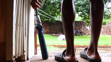 Close-up-shot-of-a-young-man-taking-umbrella-to-walk-in-the-rain-on-a-cloudy-day-at-Harare,-Zimbabwe