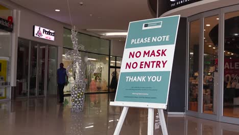 a-teal-sign-in-a-mall-reads-"No-mask-No-Entry