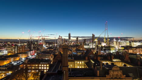 Wide-view-of-Manchester-cityscape-under-construction-with-cranes-operating-as-daylight-fades-to-night