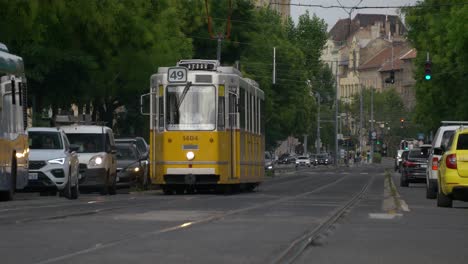 Antiguo-Tranvía-Amarillo-Acercándose-Entre-Coches-Y-Autobuses-En-Budapest.