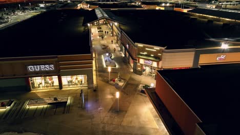 People-walking-through-open-air-mall-at-night,-with-Christmas-lights-and-trees-set-up-in-the-middle-of-the-walking-paths