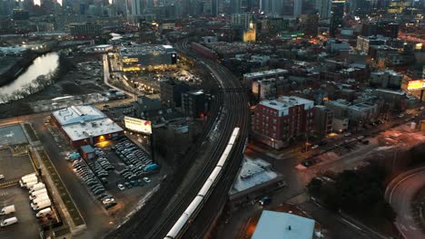 Aerial-view-following-a-evening-train-in-the-River-west-of-Chicago,-USA---tilt,-drone-shot